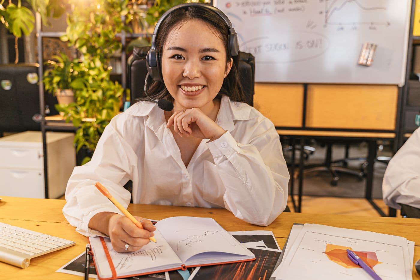 A support professional wearing a headset, smiling at her desk